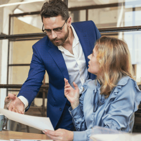 Echanges entre un homme, manager, et sa collaboratrice assise à un bureau