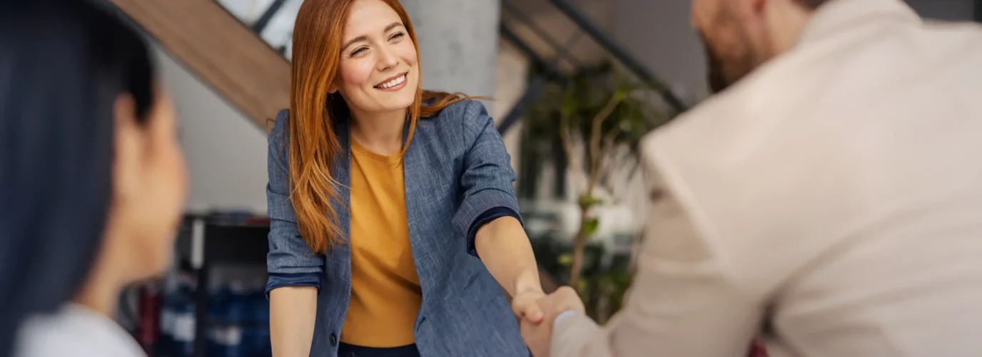 Poignée de main entre une femme souriante et un homme. Conclusion d'un accord
